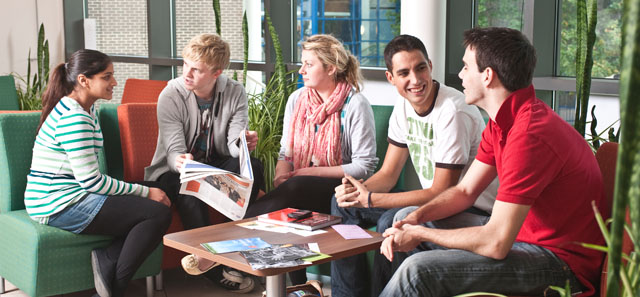 Group of students sitting around a low table smiling and chatting together