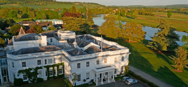 The University of Reading Greenlands campus in the sun. A big white manor house is surrounded by greenery and trees. 