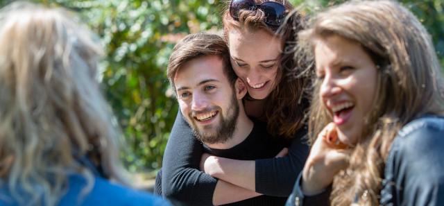 A group of master's students laughing outdoors