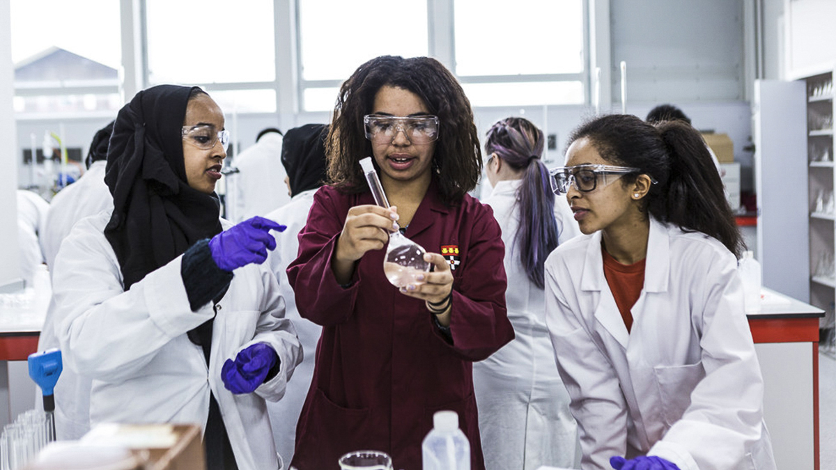 A lab technician helping two students in the lab