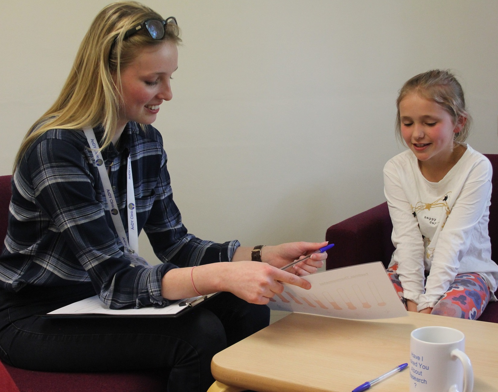 An adult and child sit at a table talking. Reading researchers have developed effective parent therapy for anxiety in children.